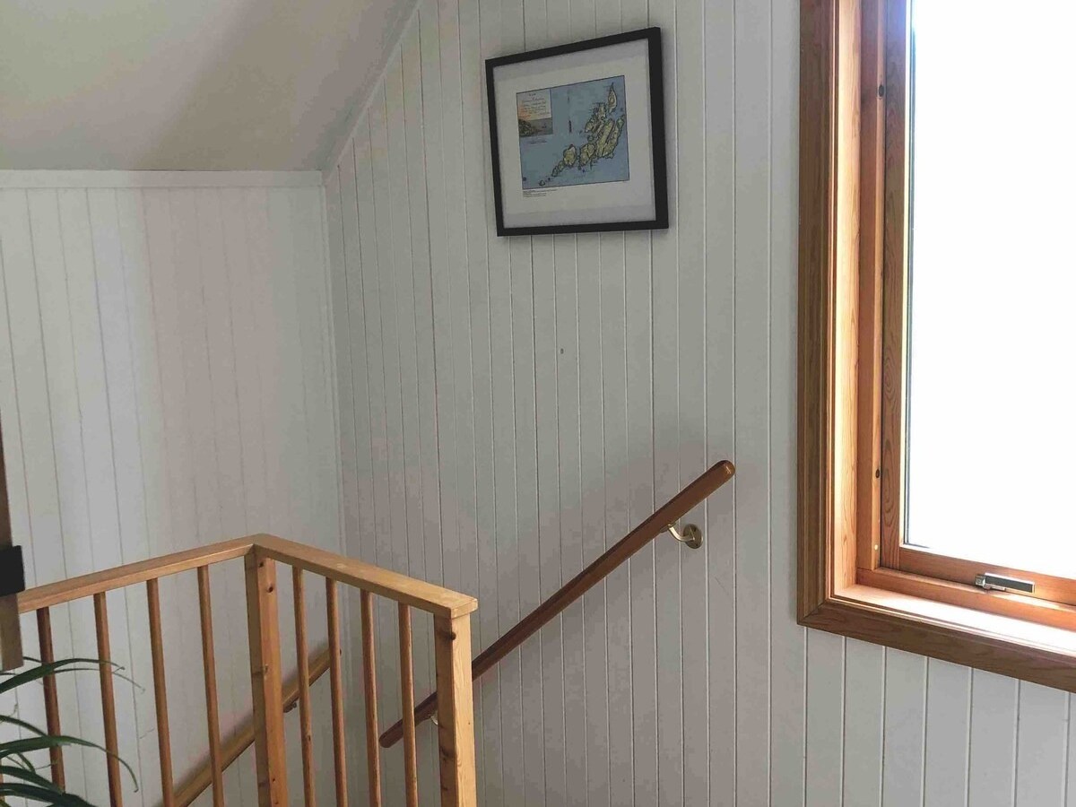 Wooden staircase with white walls, a map picture, and a large window.