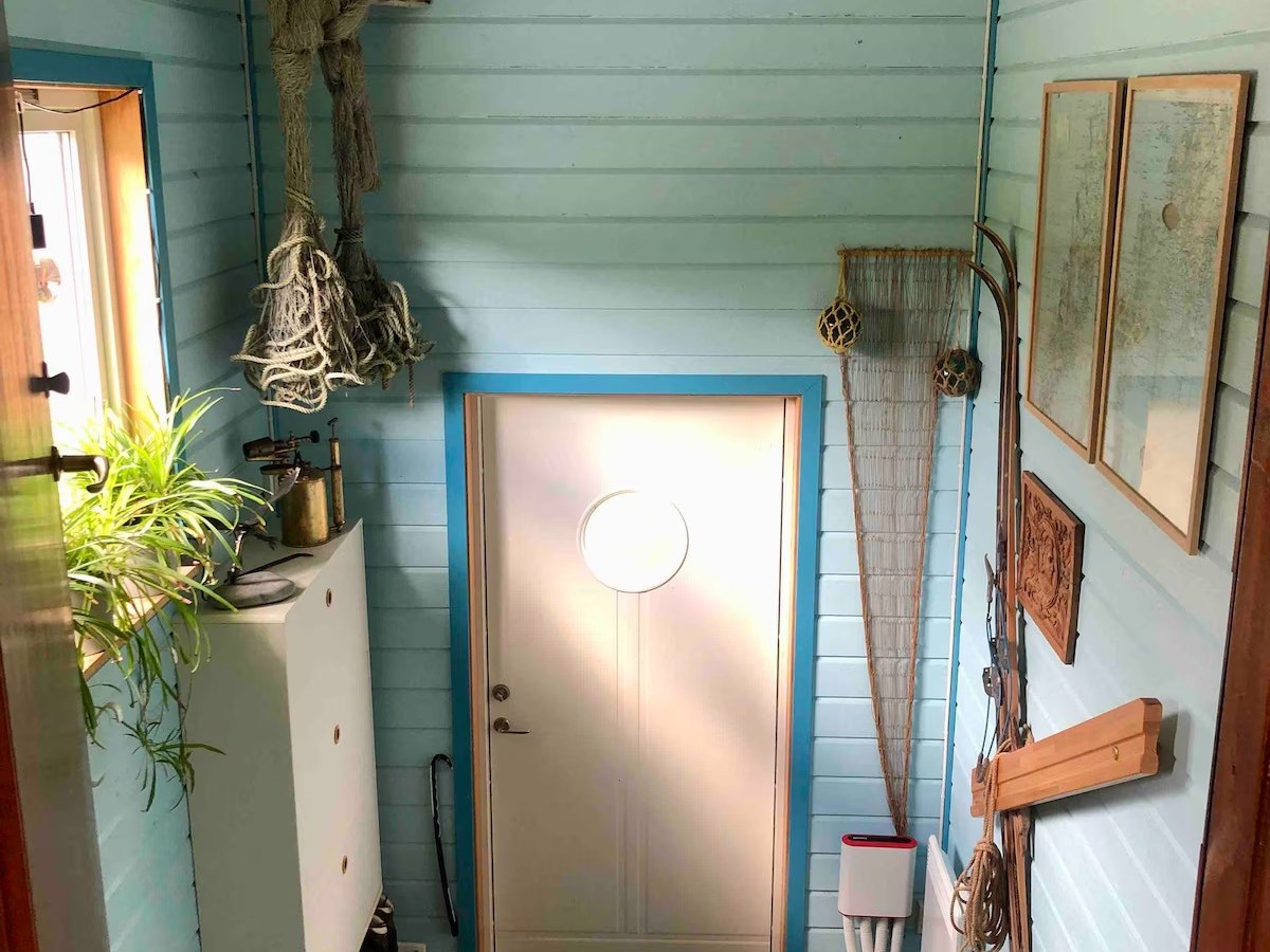 Nautical-themed entryway with blue walls, staircase, and white door featuring a round window.